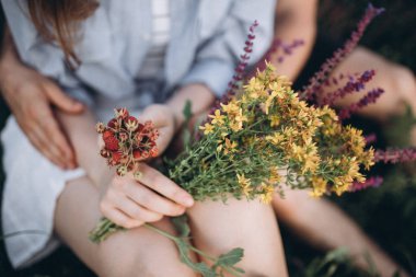 çiçek ve çilek tutan çiftin elleri ve bacakları