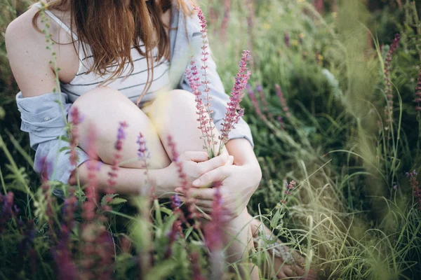 Niña sentada en la hierba alta y flores — Foto de Stock