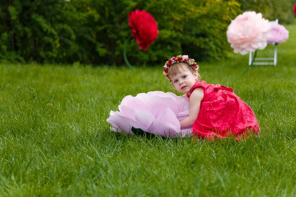 Маленькая Девочка Красном Платье Играет Зеленой Лужайке Высокими Искусственными Цветами — стоковое фото