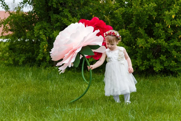 Niña Vestido Blanco Jugando Césped Verde Con Altas Flores Rosas —  Fotos de Stock