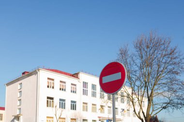 Mavi gökyüzü arka planında kapalı bir okul. Ön planda trafik işaretini durdur. Trafik yasaları ya da COVID-19 karantina kavramı. Sosyal toplantıların yasaklanması. Boşluğu kopyala.
