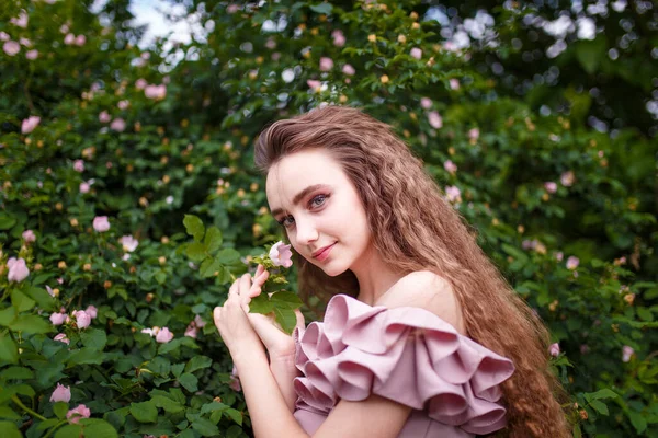 Nastolatka Kręconymi Długimi Włosami Różowym Kostiumie Kwitnącym Krzaku Wiosna Kwitnie — Zdjęcie stockowe