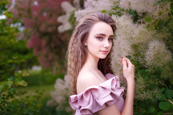 花のコティヌスCoggygriaブッシュでピンクの衣装に巻き長い髪を持つ10代の女の子 春の花と柔らかい若者のコンセプト — ストック写真