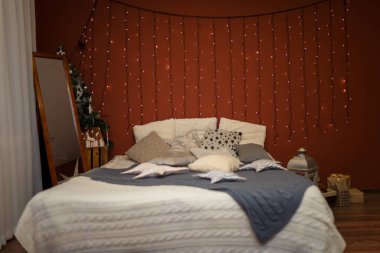 Yatak odası, yastıklar, oyuncaklar ve kahverengi arka planda çelenkler. Mutlu Noeller, mutlu yıllar ve kış tatili konsepti.