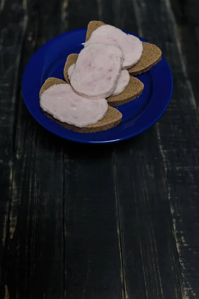 Sandwich Dark Bread Sausage Slices Blue Plate Standing Black Wooden — Stock Photo, Image