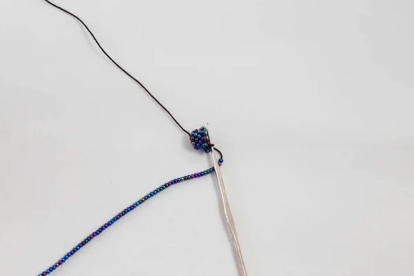 手作りのジュエリー 白い生地の背景にBijoterieを作る過程でビーズといくつかのループを持つかぎ針編みと黒の糸 ワークショップ レジャー 趣味の概念 — ストック写真