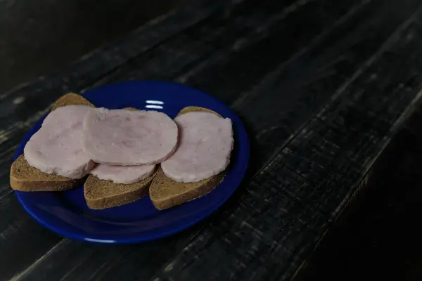 Sandwich Dark Bread Sausage Slices Blue Plate Standing Black Wooden — Stock Photo, Image