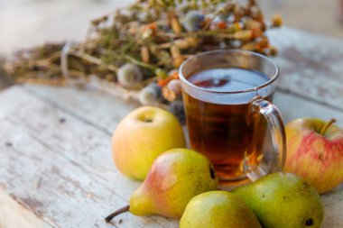 Kuru şifalı ot buketi, bir fincan bitki çayı ve biraz taze meyve, elma ve armut..