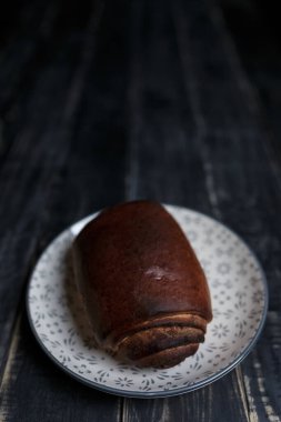 Siyah ahşap zemin üzerinde duran tarçınlı ekmek ekmeği. Lezzetli yemek, kahvaltıda ya da öğle yemeğinde atıştırmalık. Diyet, beslenme, yeme alışkanlıkları. Metin için yer. 