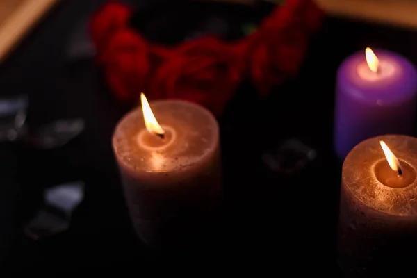 Love triangle and broken relationship concept. Broken glass  and three burning candles on black background.