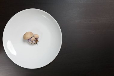 Siyah masadaki beyaz tabakta tricholoma mantarları. Diyet, beslenme, sağlıklı ve sağlıksız yeme alışkanlıkları, kilolu ya da zayıf konsept.