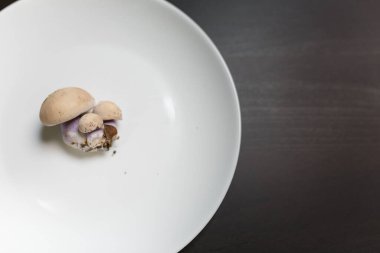 Siyah masadaki beyaz tabakta tricholoma mantarları. Diyet, beslenme, sağlıklı ve sağlıksız yeme alışkanlıkları, kilolu ya da zayıf konsept.