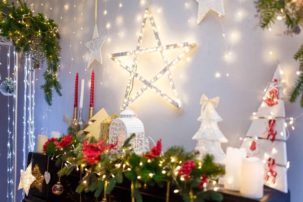 Mutlu Noeller, parlak yıldızlı mutlu yeni yıl süslemeleri, mumlar, beyaz fener, köknar dalları, ampuller, tahta oyuncak kalpler ve şömine ya da piyano üzerine sıcak çelenk ışıkları. Kış tatili kavramı.