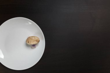 Siyah masadaki beyaz tabakta tricholoma mantarları. Diyet, beslenme, sağlıklı ve sağlıksız yeme alışkanlıkları, kilolu ya da zayıf konsept.