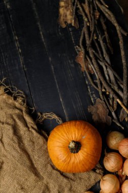 Balkabağı, kuru sonbahar dallı soğan ve siyah ahşap arka planda çuval bezi. Sonbahar hasadı, sağlıklı organik gıda konsepti. Boşluğu kopyala.