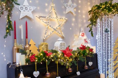 Mutlu Noeller, parlak yıldızlı mutlu yeni yıl süslemeleri, mumlar, beyaz fener, köknar dalları, ampuller, tahta oyuncak kalpler ve şömine ya da piyano üzerine sıcak çelenk ışıkları. Kış tatili kavramı.