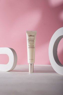 İzmail, Ukrayna. 17 Temmuz 2024. Pembe arka planda, beton dekoratif elementlerle Kore kozmetik tüpü. ISNTREE tonu ve kırışık göz kremi.