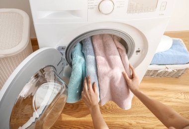 Banyo havlularını çamaşır makinesine yükleyen kişi