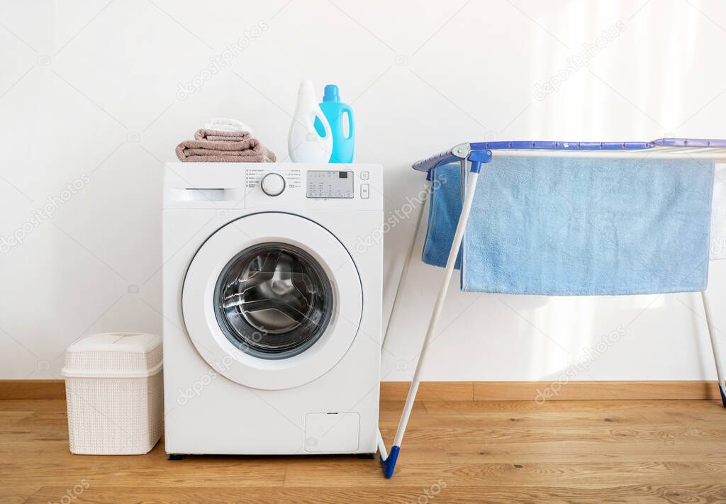 Washing machine, washing gels and towels on dryer on white background