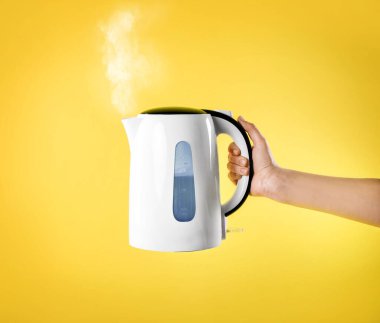 Sarı arka planda beyaz elektrikli su ısıtıcısı
