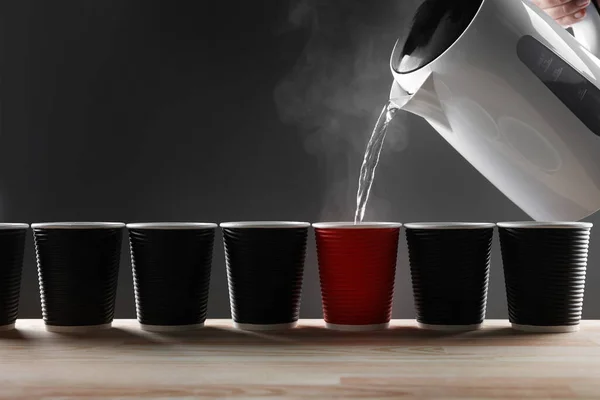 Electric white kettle puring water in cups on grey background — Stock Photo, Image