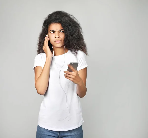 Beautiful african woman holding phone in his hand, on gray background