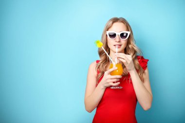 Güzel bir kadın mavi arka planda kokteyl içer.