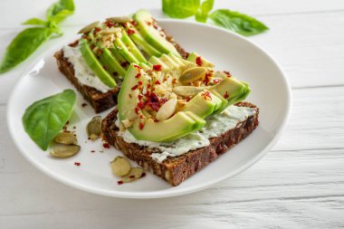 Beyaz ahşap kaplama tabakta baharatlı avokado sandviçleri..