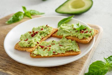 Beyaz arka planda guacamole soslu gevrek sandviç..