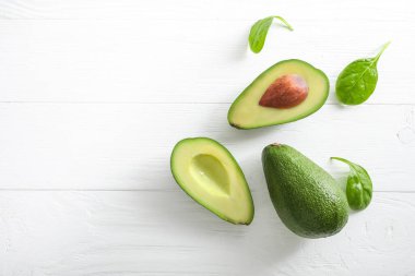Beyaz ahşap arka planda tam ve yarı yarıya avokado meyvesi. Üst Manzara. Boşluğu kopyala.