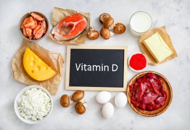 Beyaz zemin üzerindeki yüksek D vitamini kaynakları: süt, karaciğer, karides, somon, peynir, tereyağı, kırmızı havyar, yumurta, mantar, süzme peynir. Üst görünüm.