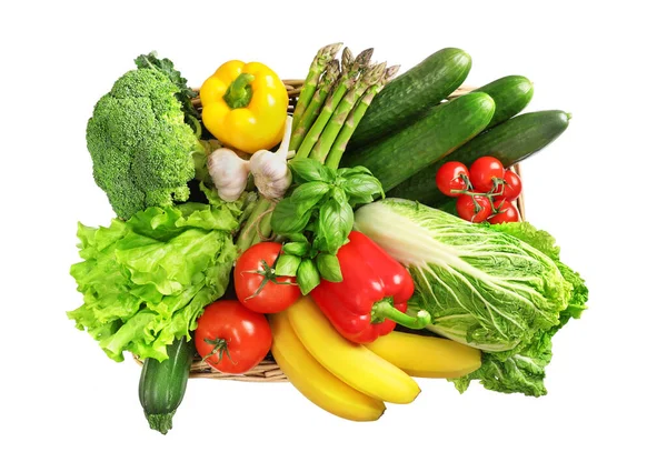 Wicker basket full of fresh vegetables and herbs isolated on white background. Vegetarian healthy food.