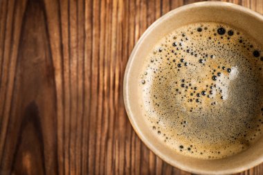 Tahta arka planda, kağıt bardakta sade kahve. Üst görünüm.