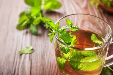 Nane çayı cam bardakta, ahşap arka planda..