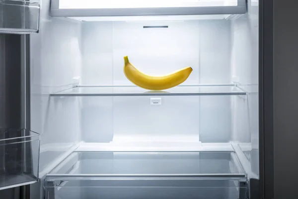 One banana in open empty fridge. Weight loss diet concept.