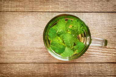 Ahşap zemin üzerinde cam bardakta nane çayı. Üst Manzara. Boşluğu kopyala.