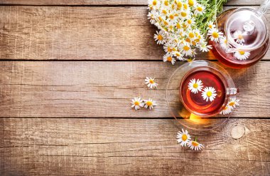 Cam fincanda papatya çayı ve ahşap arka planda çiçek tomurcukları olan çaydanlık. Üst Manzara. Boşluğu kopyala.