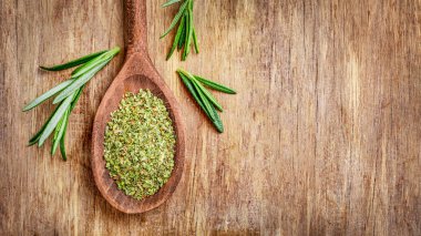 Tahta kaşıkta kurutulmuş kekik otu ve ahşap arka planda taze biberiye filizi..