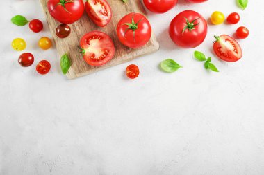 Beyaz zemin üzerinde taze olgun domates ve fesleğen yaprakları. Üst Manzara. Boşluğu kopyala.