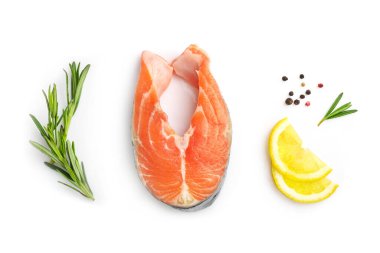 Beyaz arka planda çiğ somon, limon dilimleri ve biberiye filizlerinin üst görüntüsü.