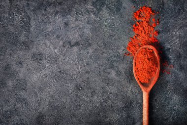 Koyu arkaplanda kırmızı biber tozu dolu tahta kaşık. Üst Manzara. Boşluğu kopyala.