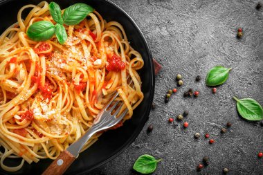 Domatesli İtalyan makarnası, parmesanlı peynir ve siyah arka planda fesleğen. Üst görünüm.