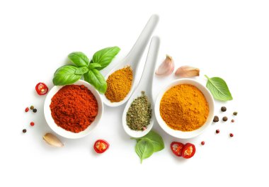 Beyaz arka planda izole edilmiş kâse ve kaşıkların çeşitli baharatların üst görünümü.