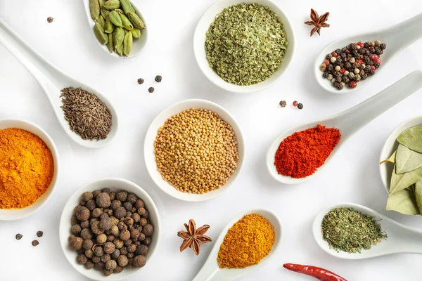 Beyaz arka planda izole edilmiş çeşitli baharatların ve kaşıkların üst görüntüsü. Düz yatıyordu.