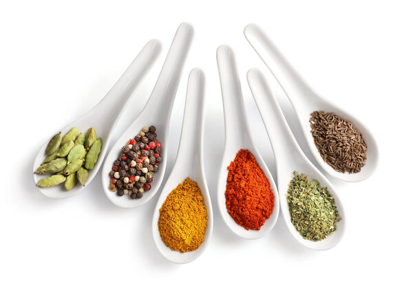 Top view of various spices in spoons isolated on white background.