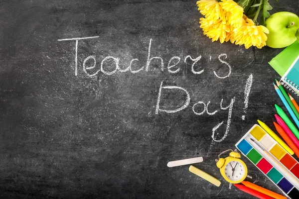 Teacher\'s day greeting card on black chalkboard background. Top view.