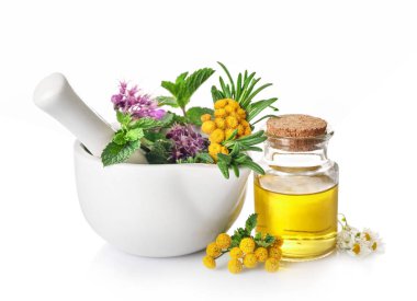 Havan topuzlu otlar ve beyaz arka planda izole edilmiş cam şişedeki organik aroma yağı. Bitkisel tıp konsepti.