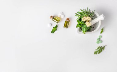 Havan topuzunda tıbbi bitkiler, cam şişelerde organik aroma yağı ve beyaz arka planda izole edilmiş bitkisel haplar. Üst Manzara. Uzayı kopyala Bitkisel tıp konsepti.