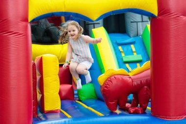 Renkli Bahçesi trambolin üzerinde atlama çocuk. Çocuklar şişme sıçrama kalede anaokulu doğum günü partisi aktivite üzerinde atlamak ve genç çocuk Merkezi oynamak. Küçük kız açık havada yaz aylarında oynamaktan.