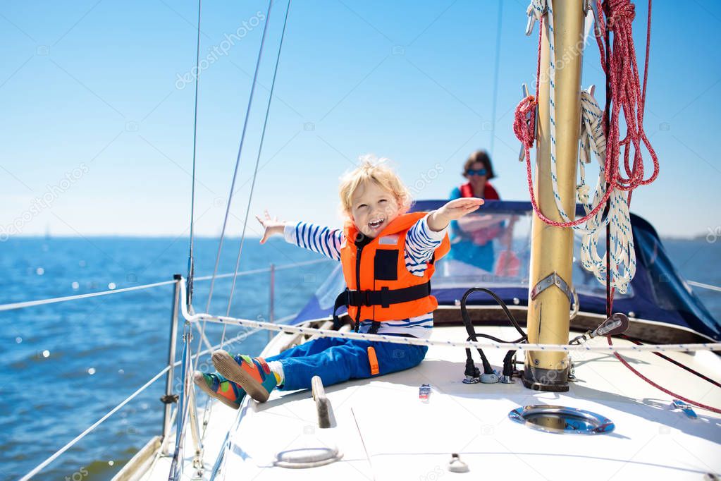 I bambini salpano in barca in mare. Bambino che naviga in barca. Un ragazzino con giubbotti salvagente viaggia su una nave oceanica. Ai bambini piace la crociera in barca. Vacanze estive per la famiglia. Giovane marinaio sul ponte anteriore barca a vela.